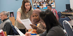 teacher works with adult English language learners students in ESL classroom